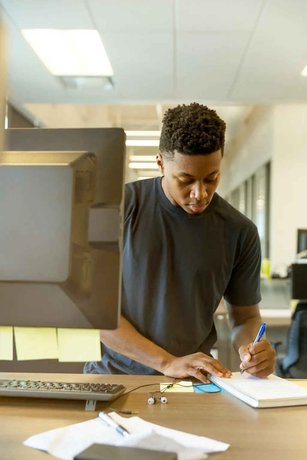 A man working on paperwork by a computer.