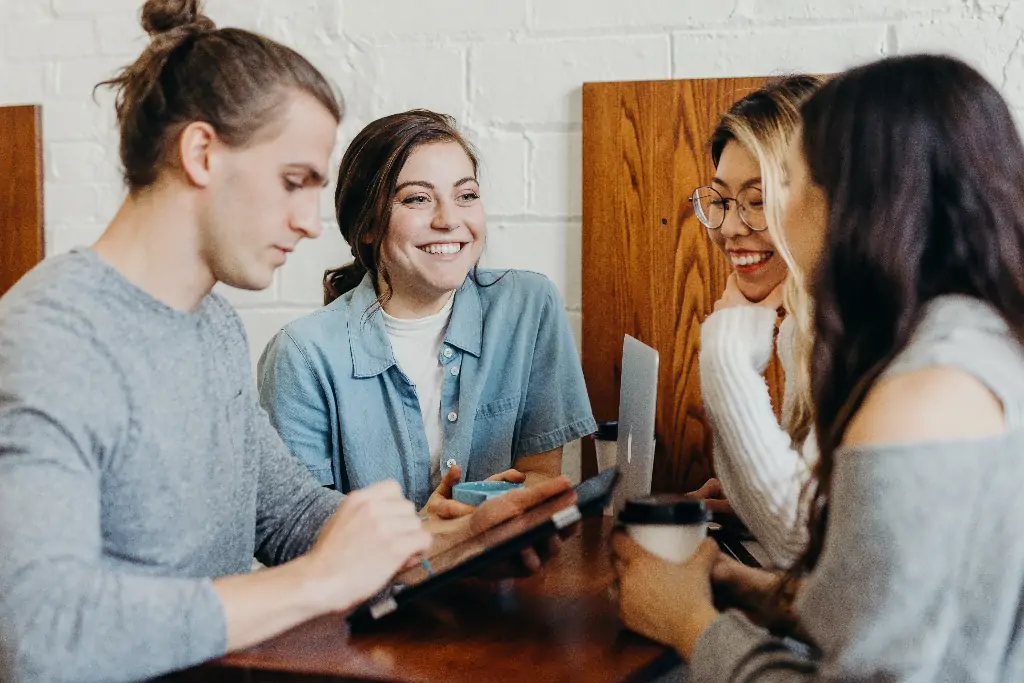 A group of young adults sitting at a table in a cafe, working together.